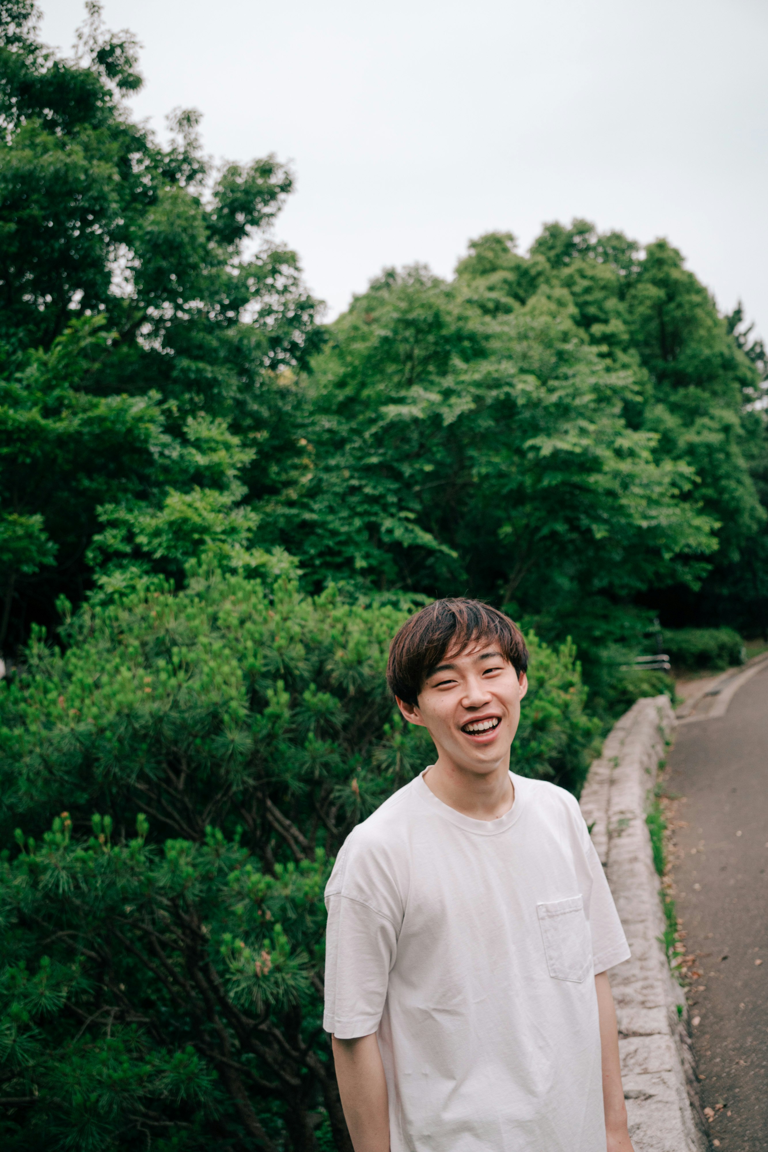 uomo sorridente in piedi con sfondo di foresta verde