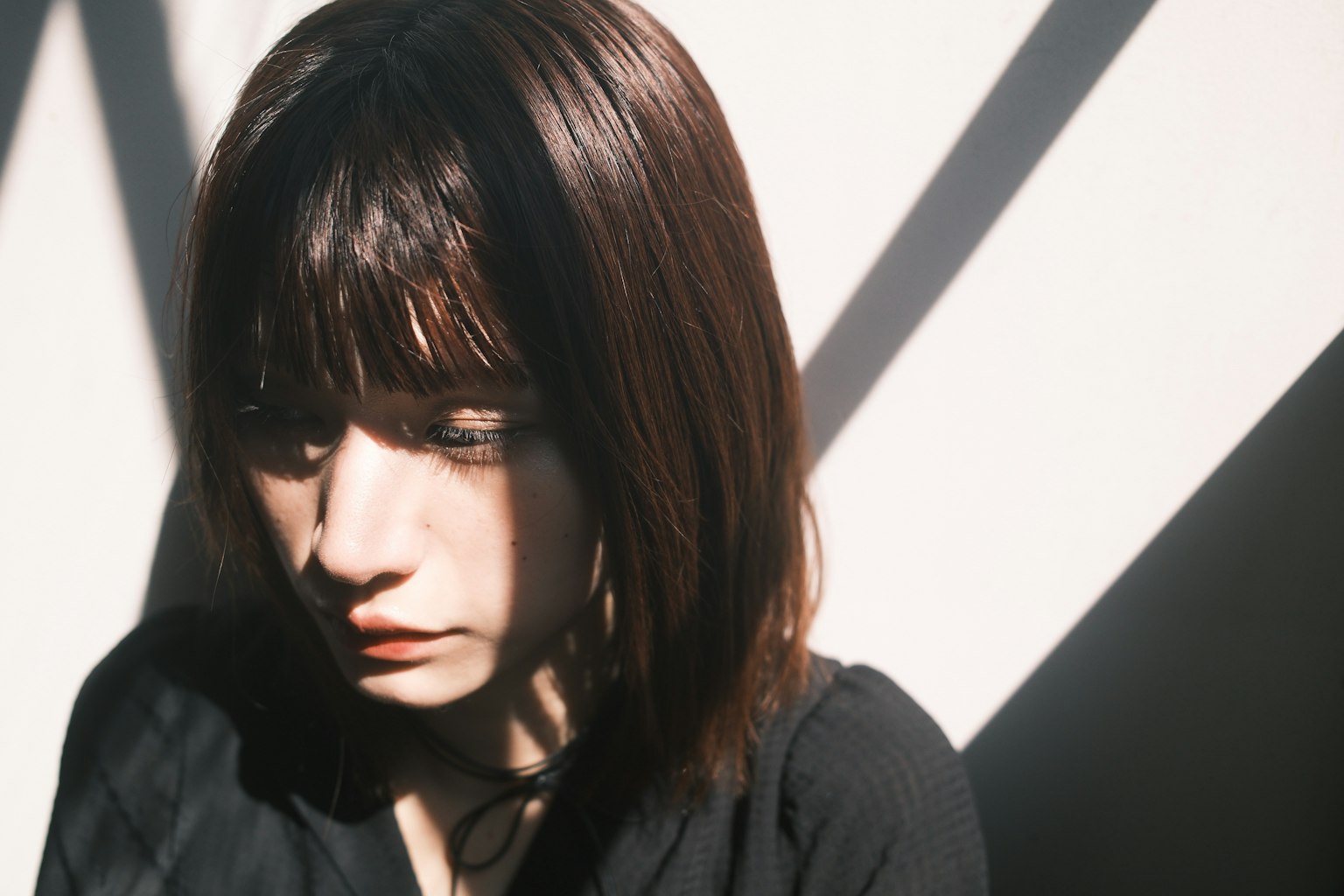 女性が影の中で考え込んでいる様子