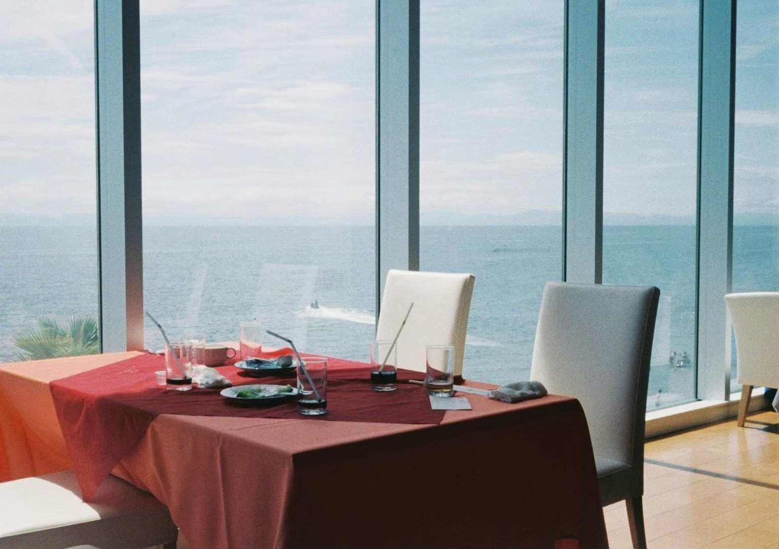 Restaurant table overlooking the sea red tablecloth and white chairs