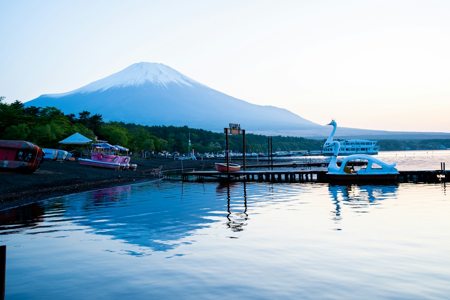 富士山倒映在湖面上的風景，旁邊有一隻天鵝形狀的船
