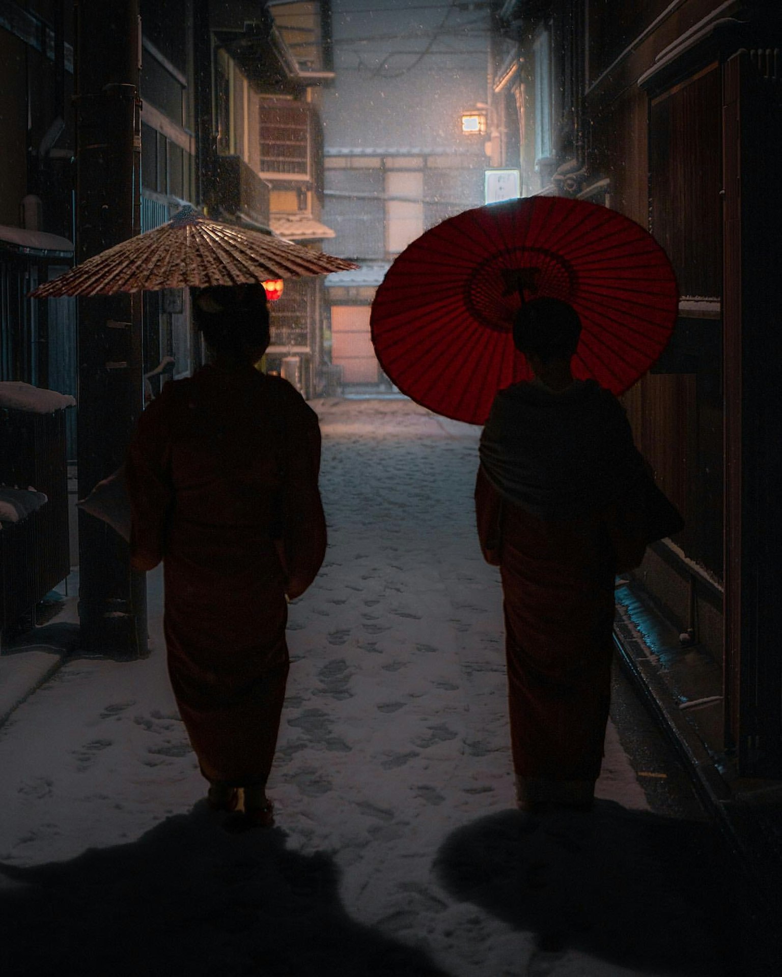 兩位身穿和服的人在雪中的小巷中走