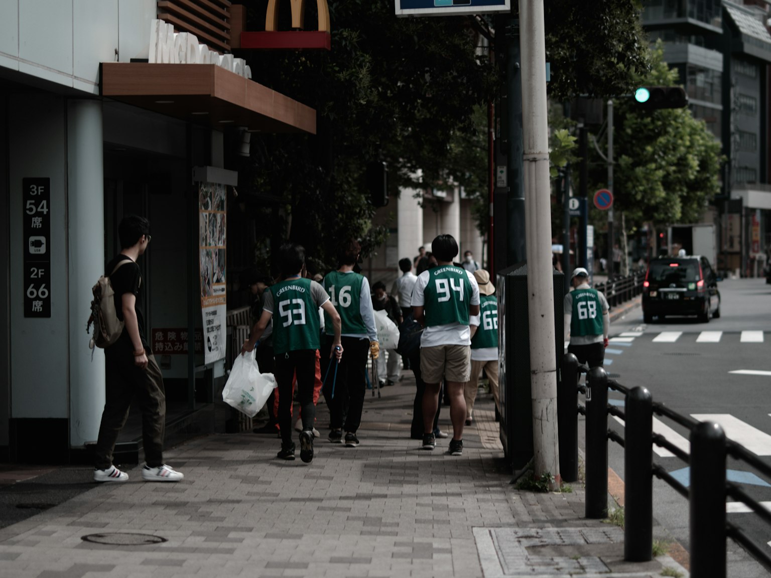 Grupo de personas con camisetas verdes caminando por la acera