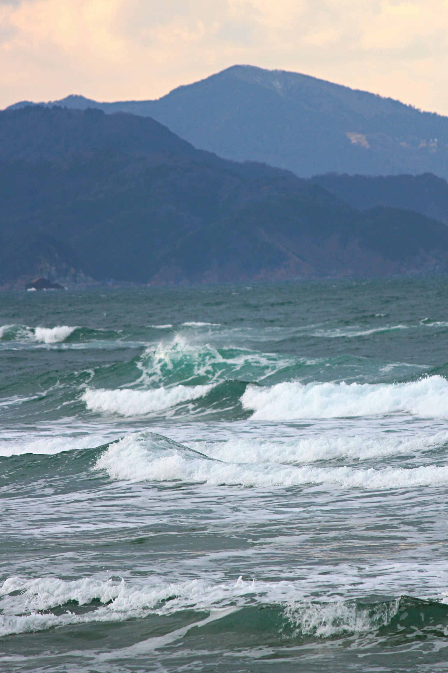 A scenic view of blue ocean waves with mountains in the background