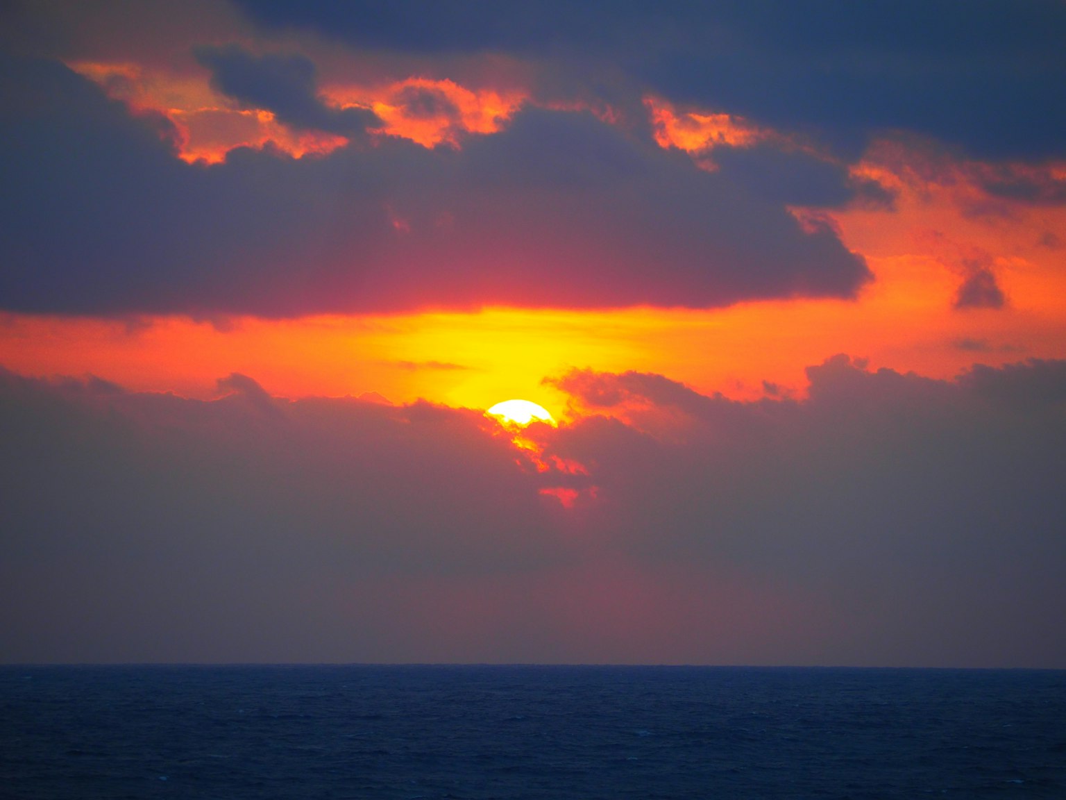 Tramonto sull'oceano con nuvole arancioni