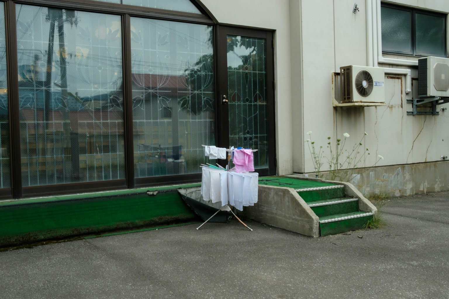 Cảnh ngoài trời với quần áo phơi bên cạnh một tòa nhà có cửa sổ và máy điều hòa không khí