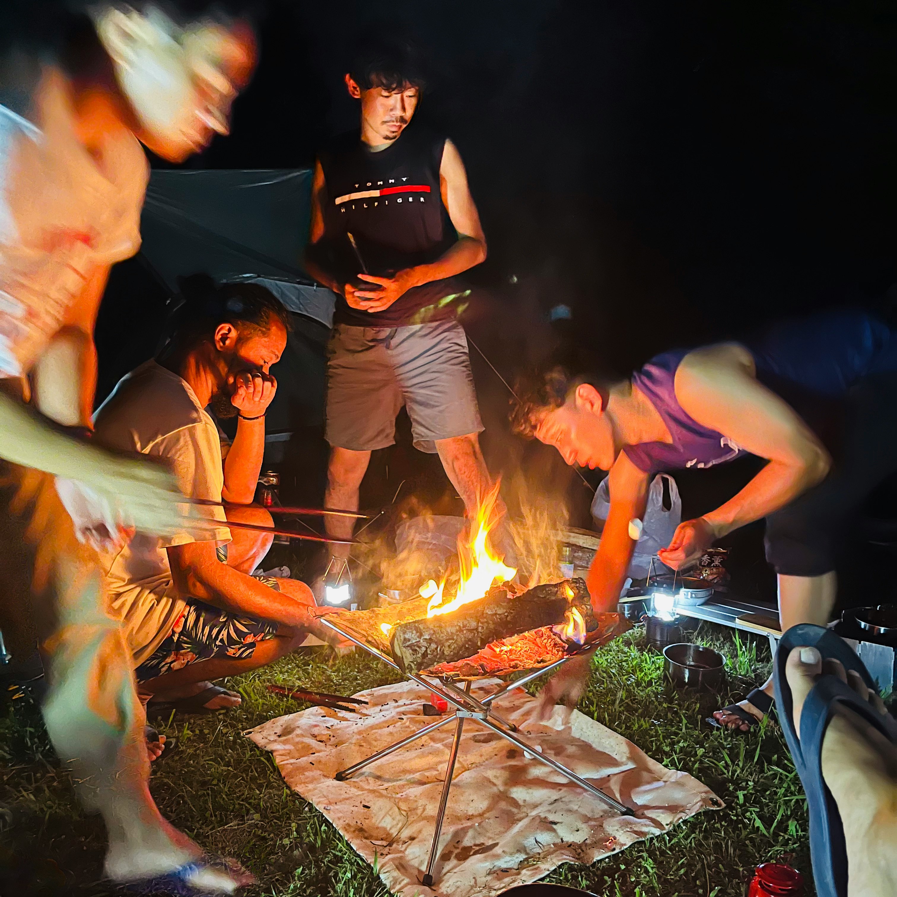 焚き火を囲む夜の屋外バーベキューの集まり