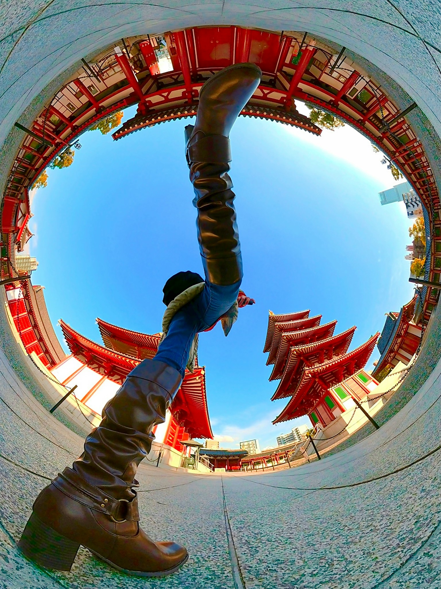A unique perspective photo featuring a person in tall boots with red buildings in the background