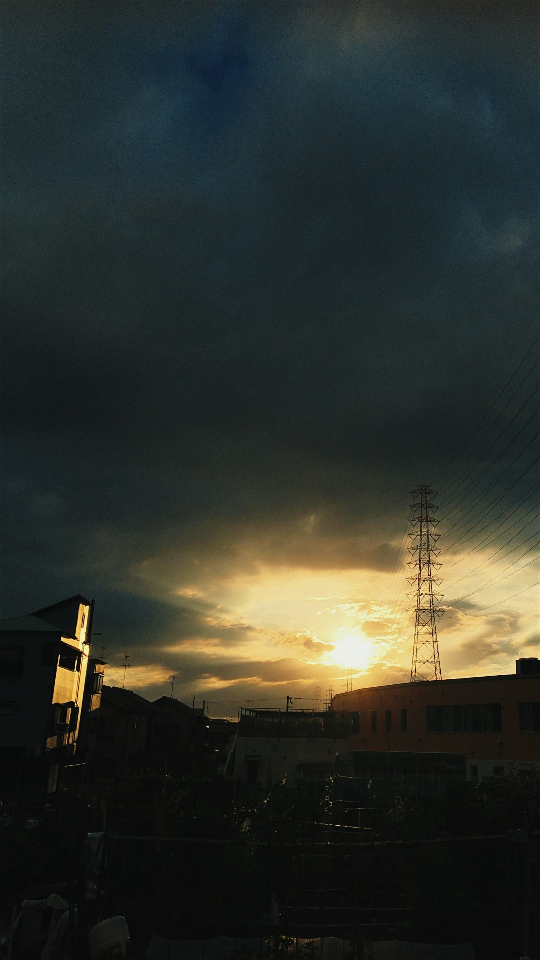 夕日に照らされる空と電線・送電塔のシルエット