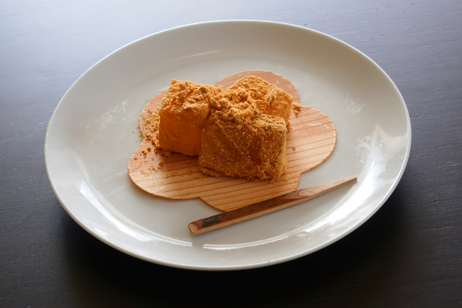 Presentazione di dessert giapponese con dolce quadrato su un piatto bianco cosparso di polvere di kinako
