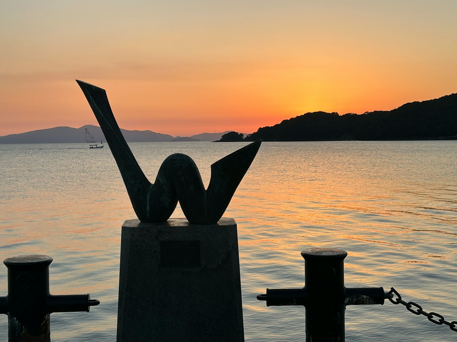 抽象雕塑在海上色彩斑斓的日落背景下的剪影