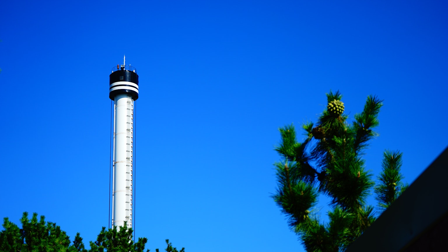 Alto torre contro un cielo blu chiaro con alberi verdi
