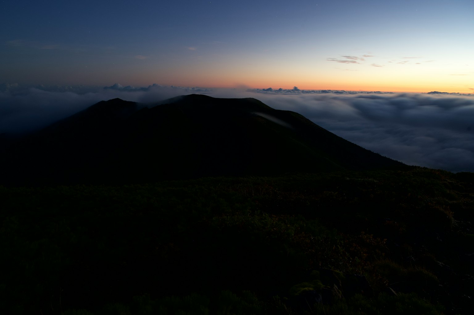 Silhouette of mountains above a sea of clouds at sunset