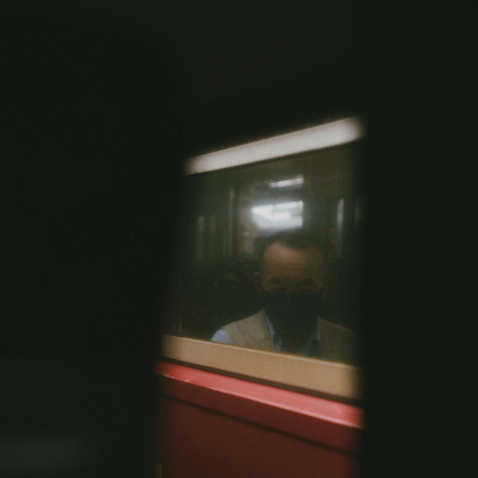 Verschwommene Reflexion eines Mannes in einem Fenster mit dunklem Hintergrund