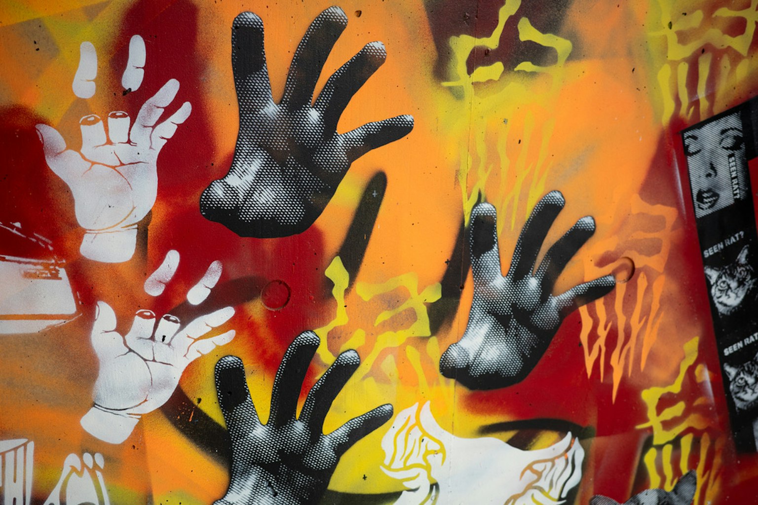 Art de graffiti représentant des mains sur un fond orange et rouge vif