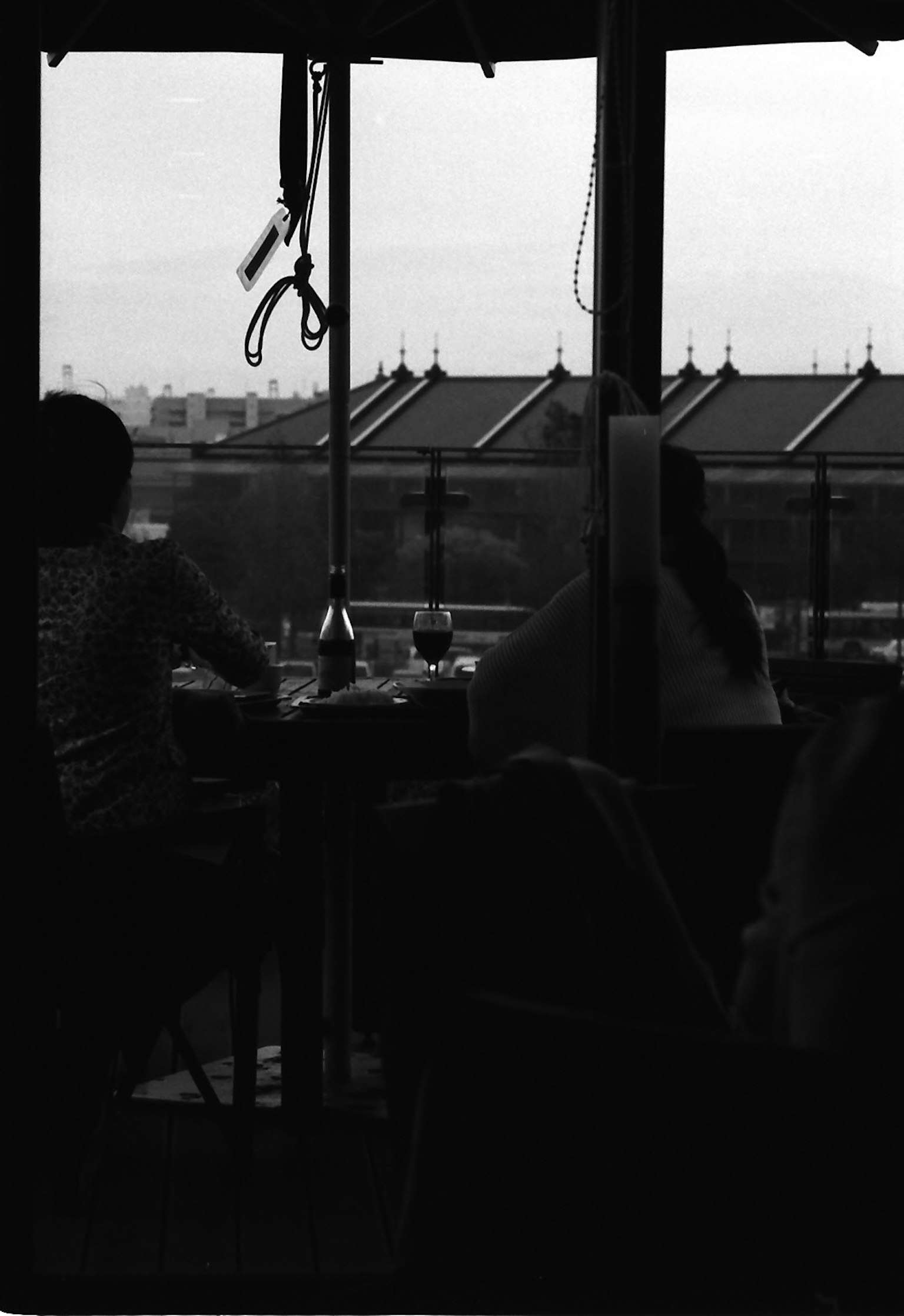 Black and white image of people sitting by a window with a view outside