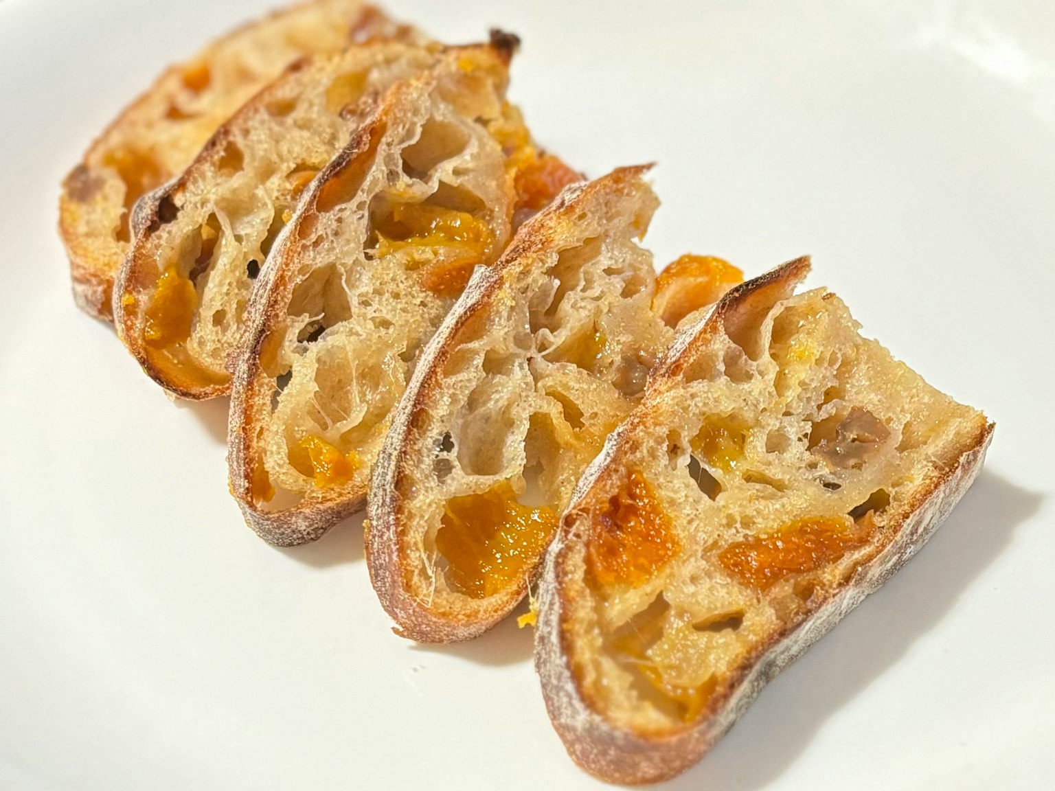 Sliced bread with dried fruits arranged on a white plate