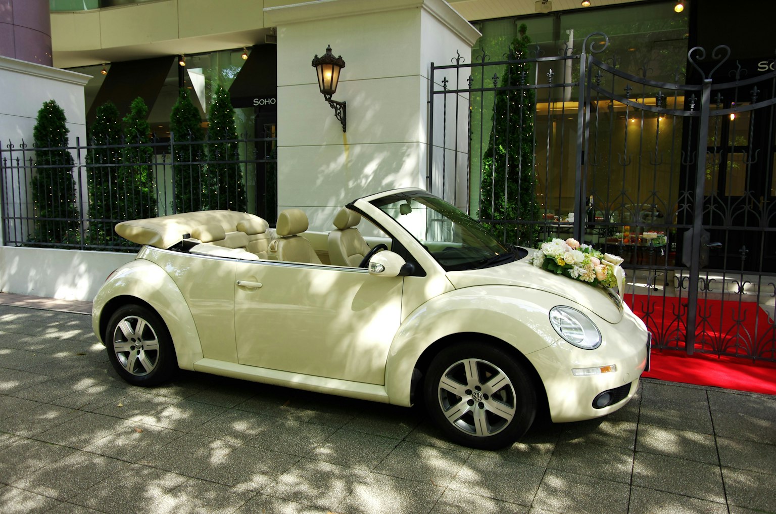 Une voiture décapotable Beetle blanche décorée de fleurs garée devant un bâtiment élégant