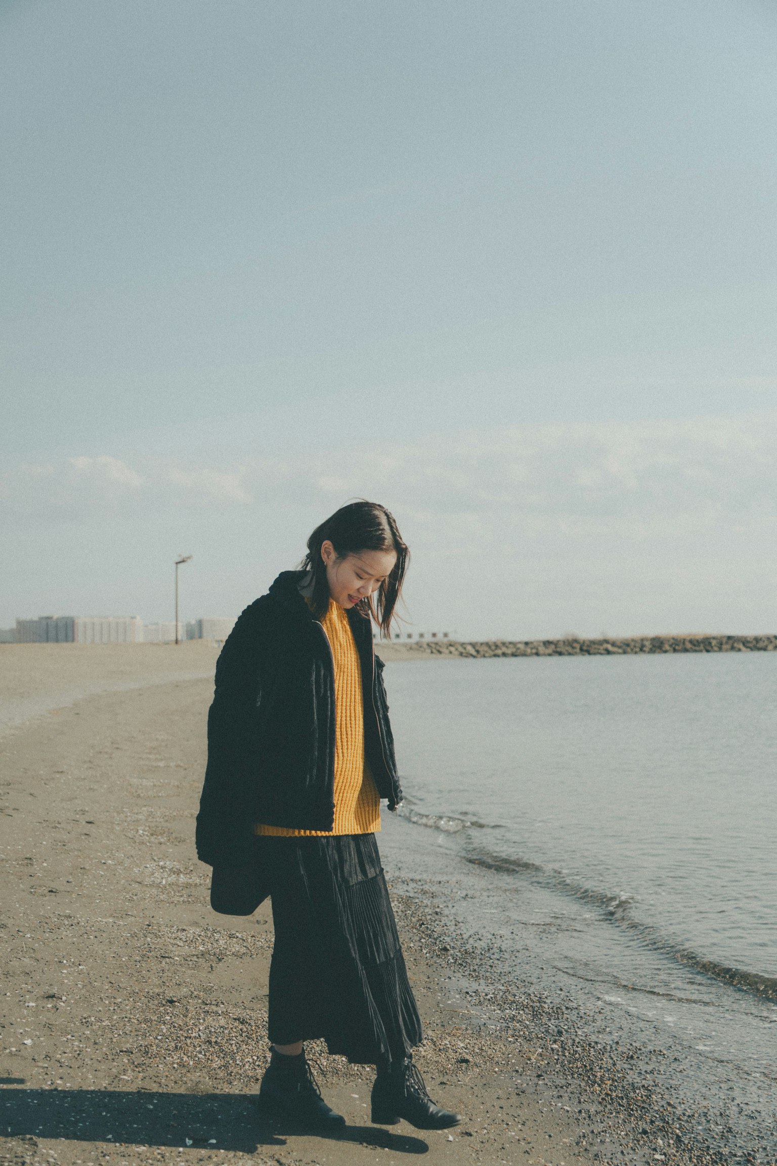 海灘上走的女性穿著黑色外套和黃色上衣