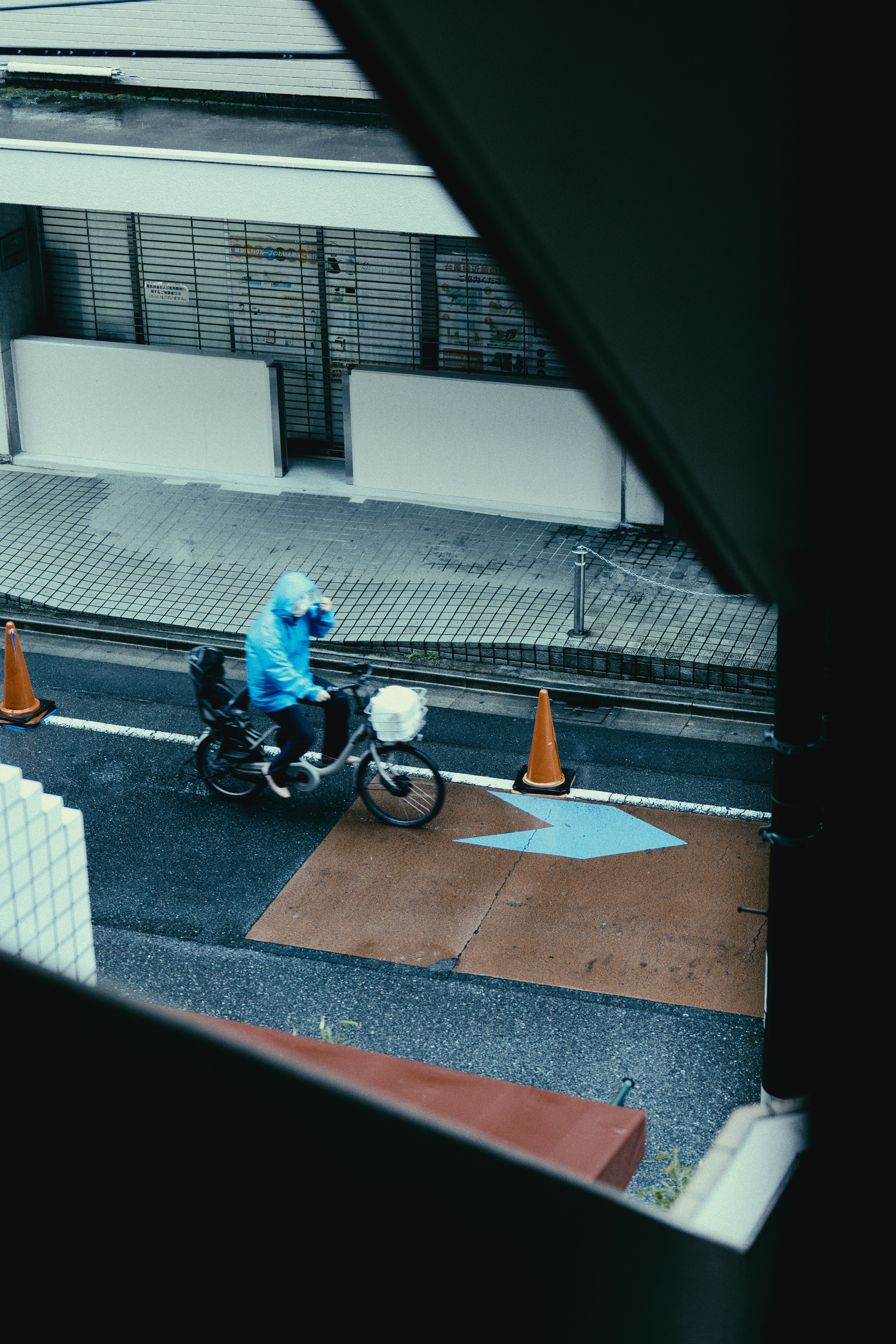 雨上がりの路地で並ぶ自転車とコーンのある通路