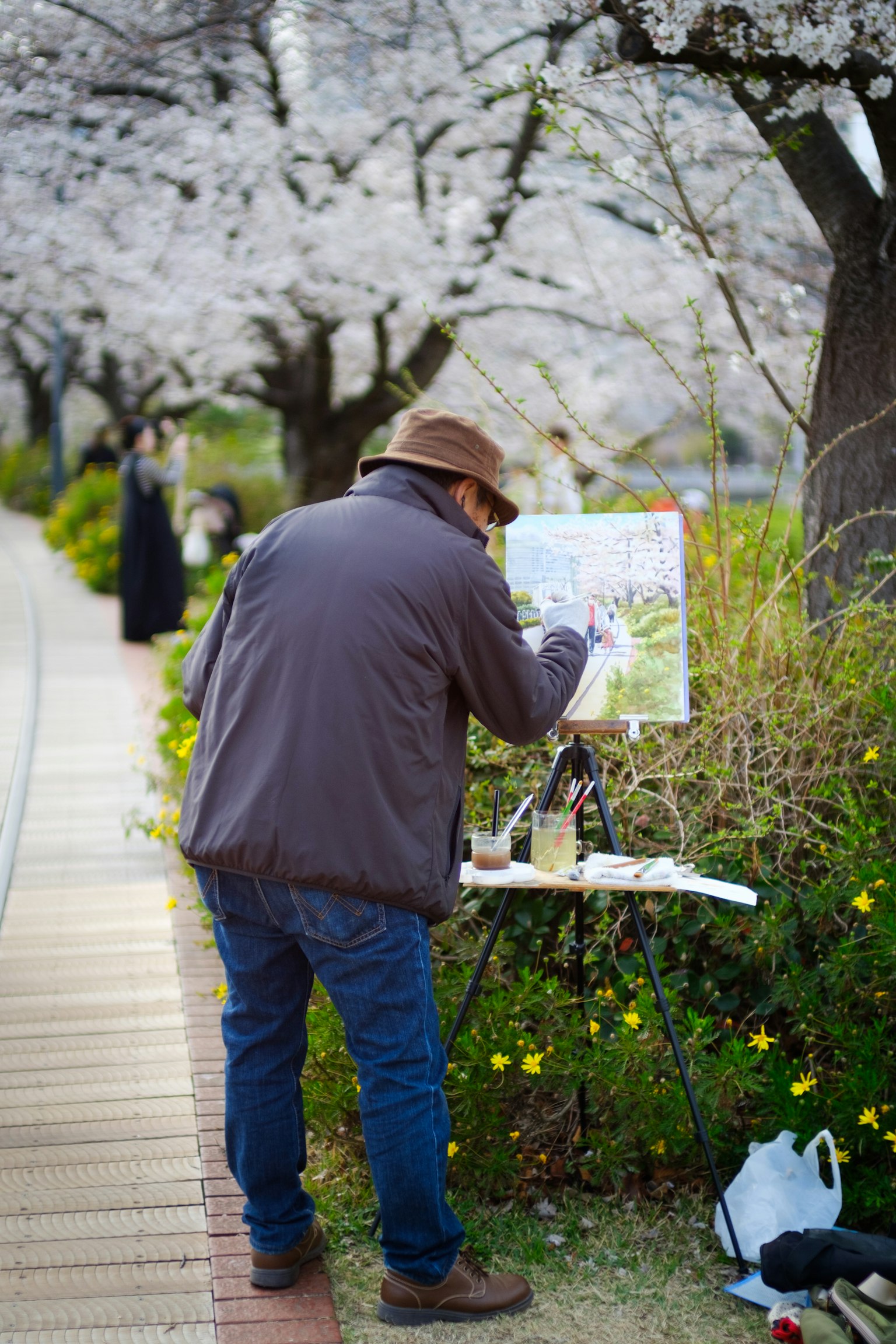 Ein Mann malt unter Kirschblütenbäumen