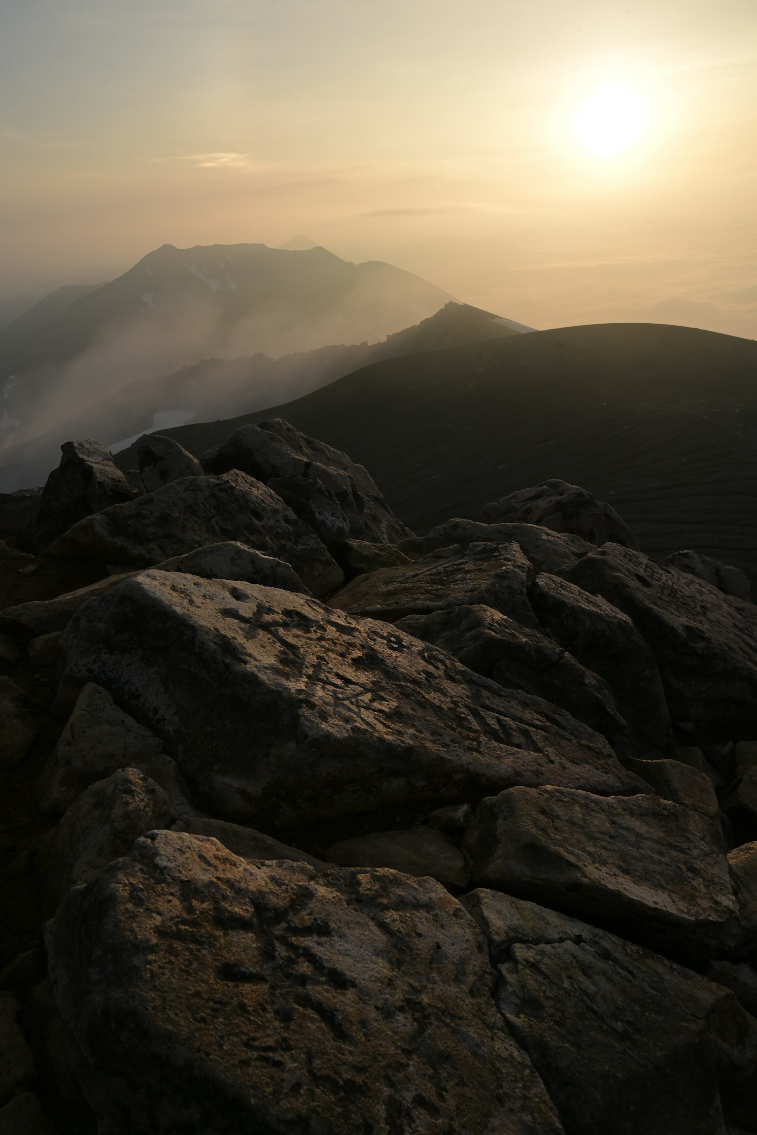 Pemandangan matahari terbenam dengan gunung dan close-up batu