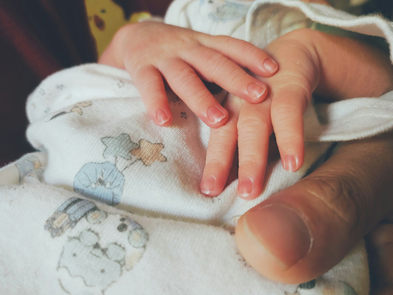 La piccola mano di un bambino accoccolata contro la mano di un adulto
