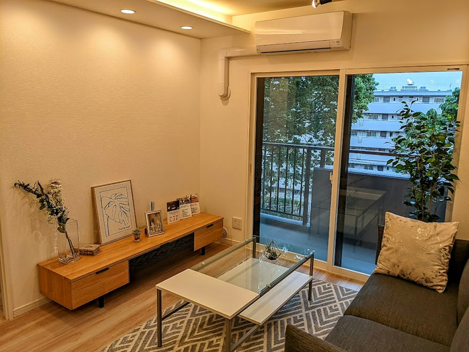 Sala acogedora con tonos de colores naturales Paredes brillantes y grandes ventanas Muebles simples y elegantes Sofá cómodo y mesa de café de vidrio
