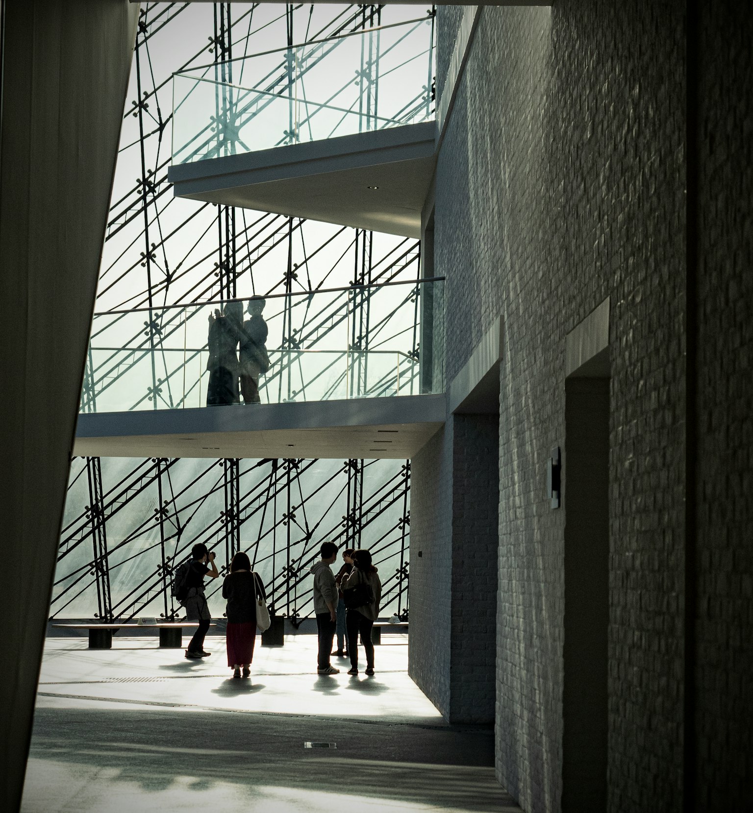 Interior museum modern dengan dinding kaca dan patung terlihat