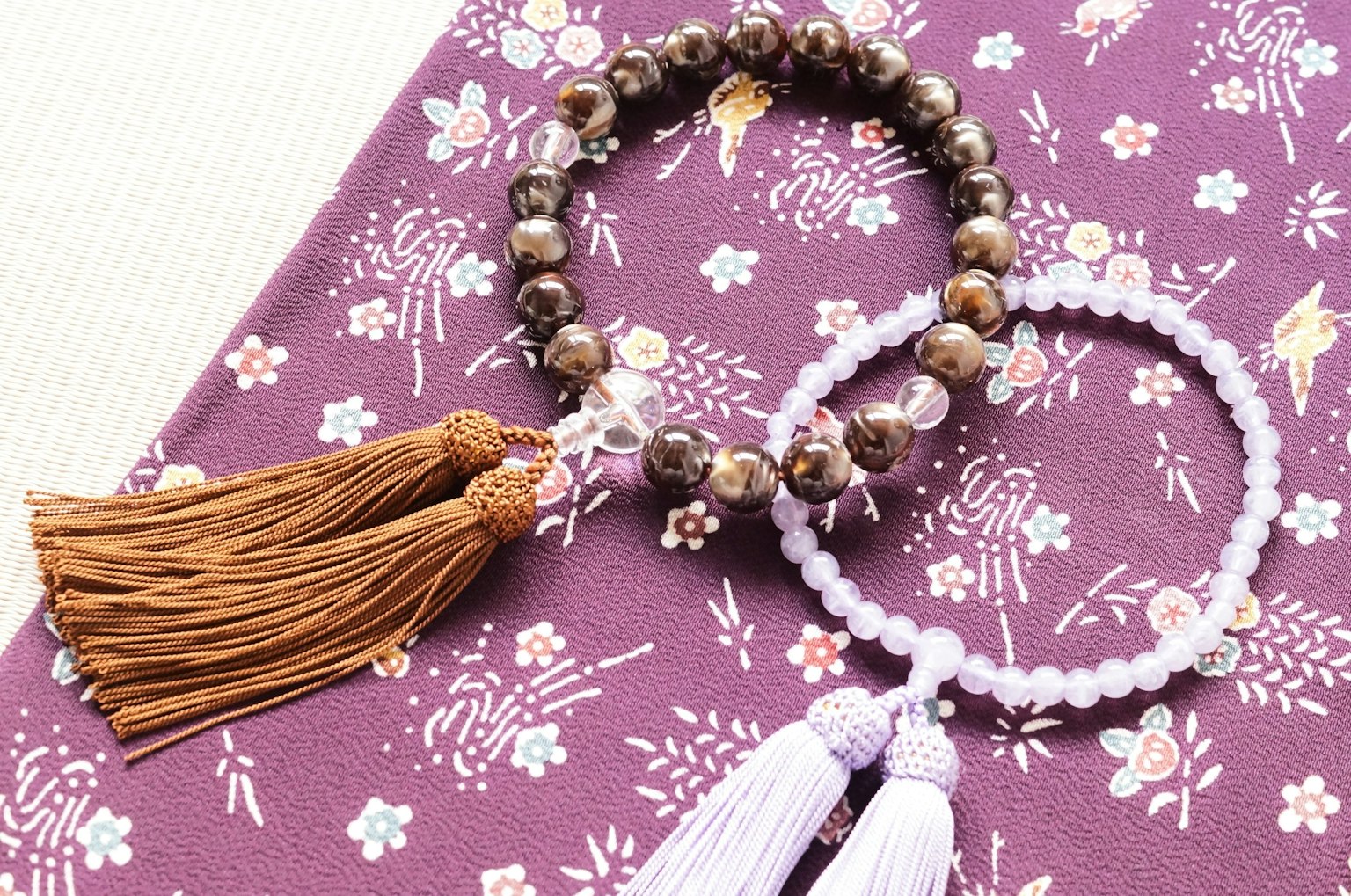ภาพของสร้อยข้อมือสองเส้นพร้อมพู่บนผ้าสีม่วงลาย