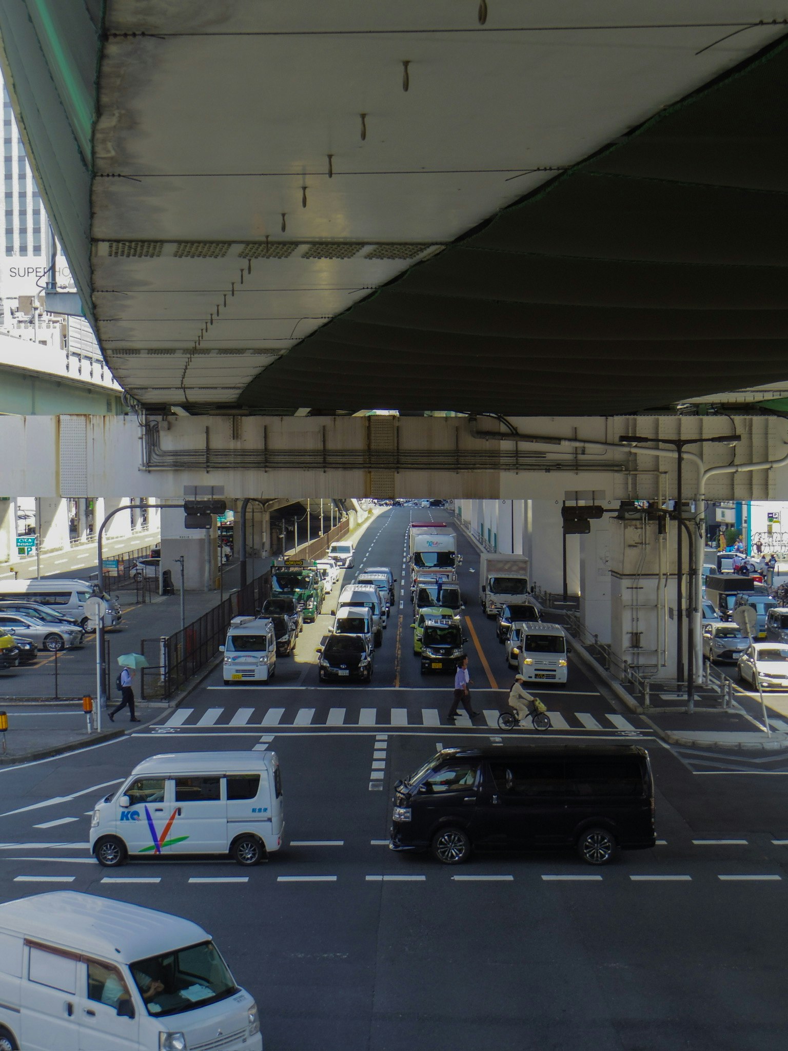 高架下の交差点に集まる車両と交通信号