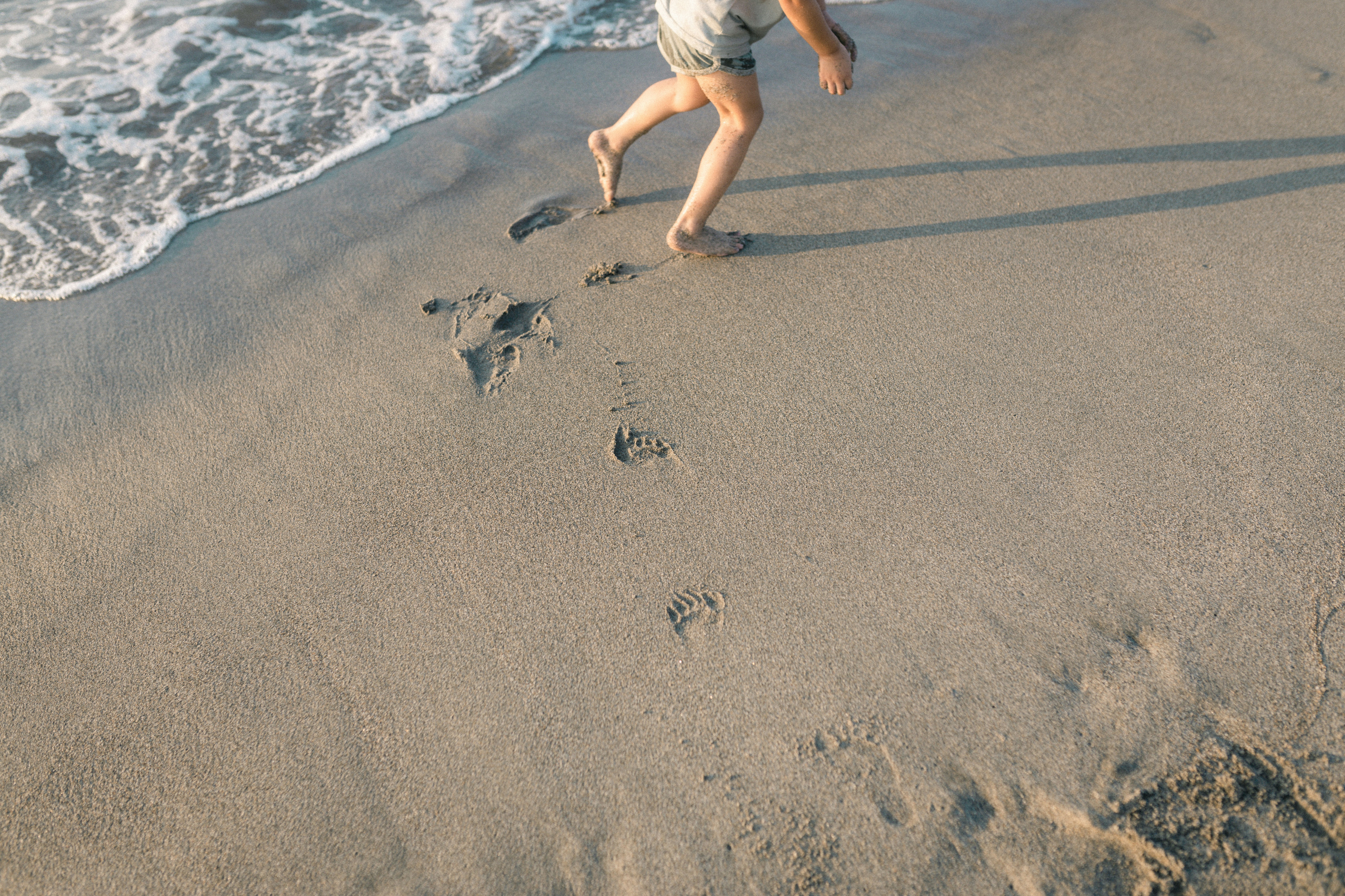 Child running on the beach leaving footprints in the sand