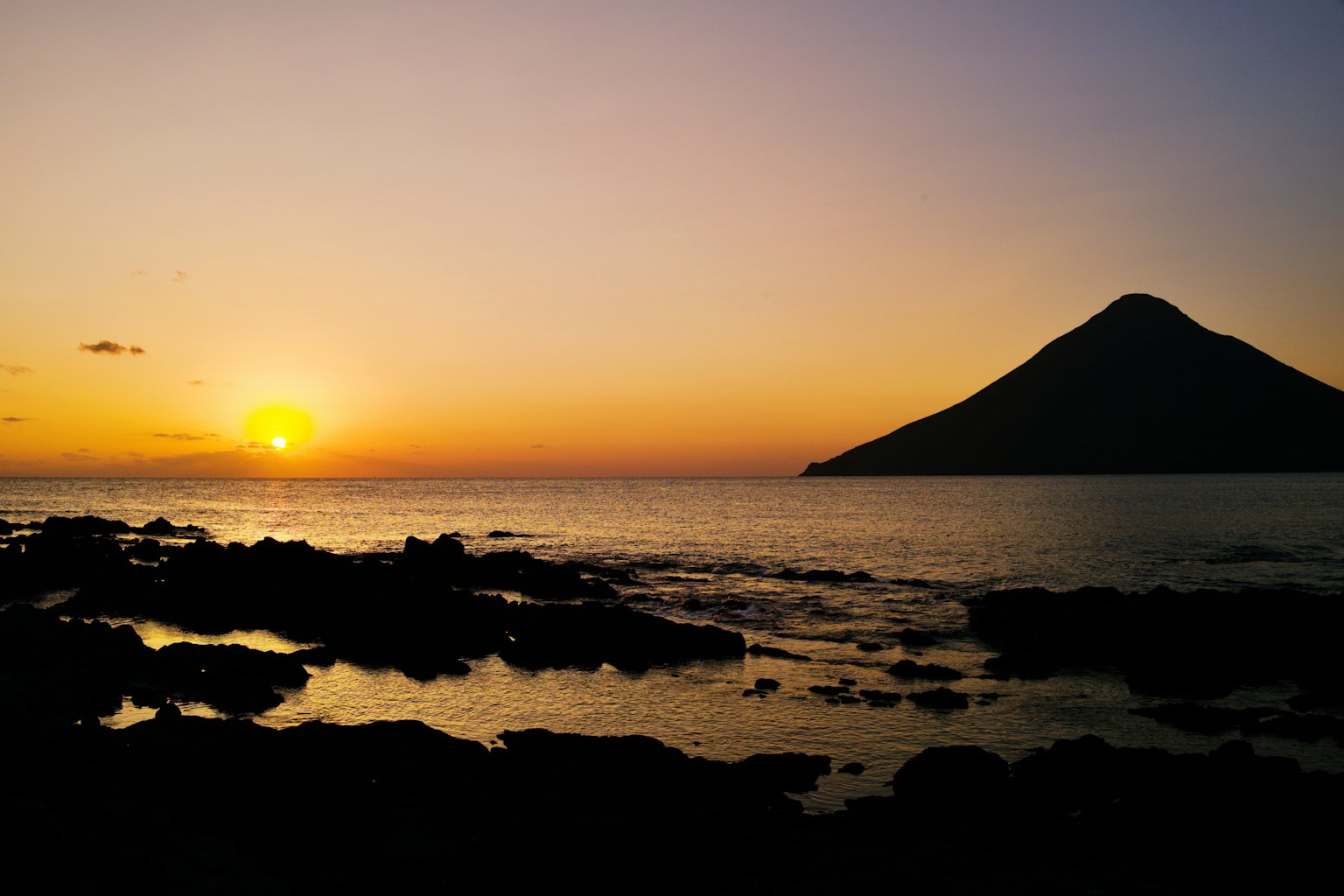 Beautiful landscape with sunset over the sea and mountain silhouette
