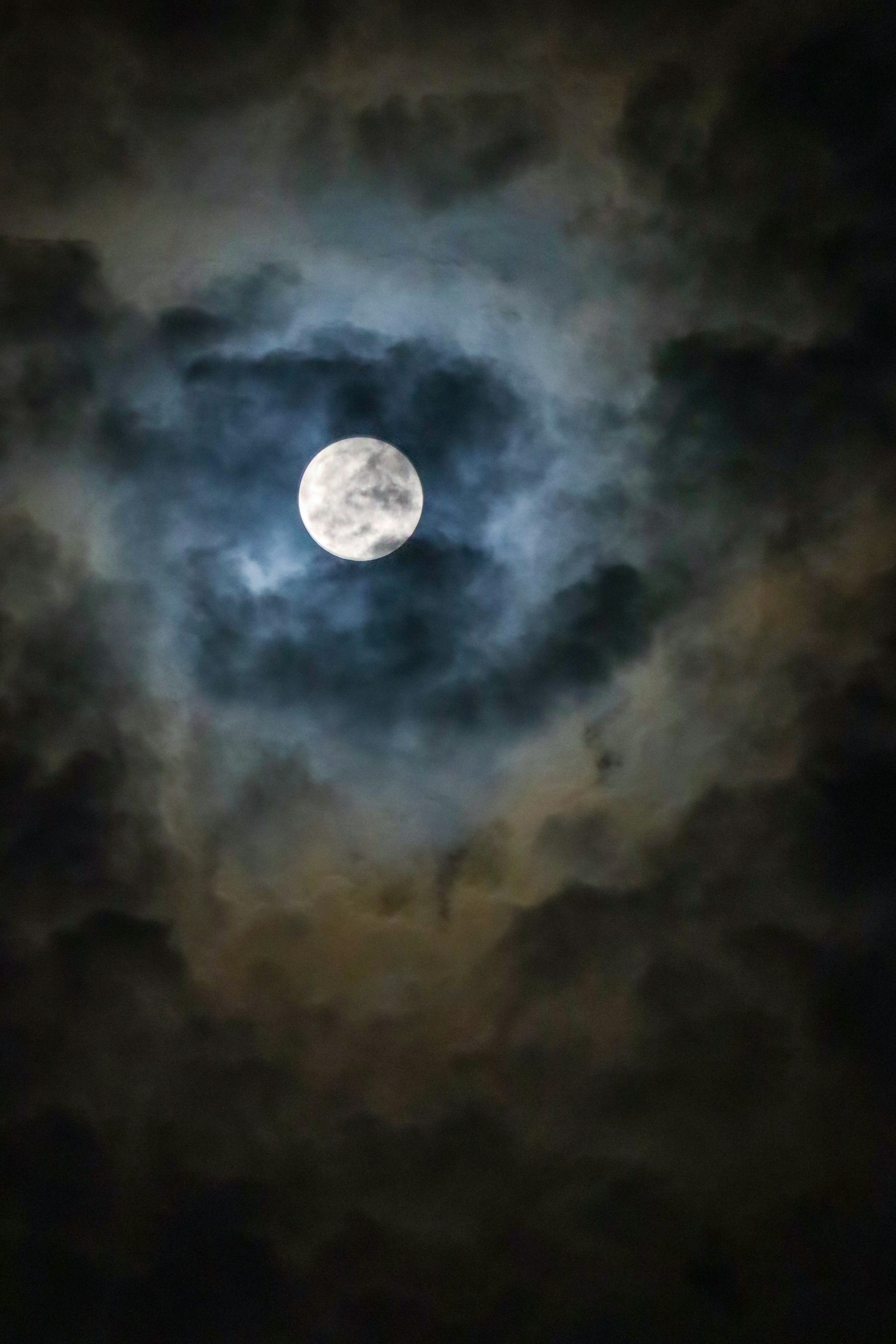 Bulan terang dikelilingi awan gelap di malam hari