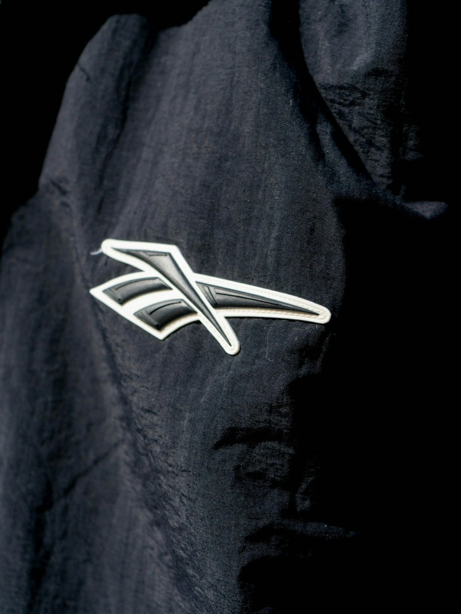 White arrow logo design on black fabric