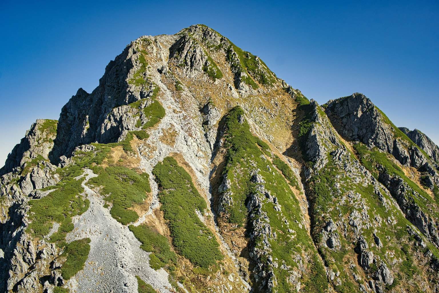 Foto de un pico montañoso escarpado con hierba verde