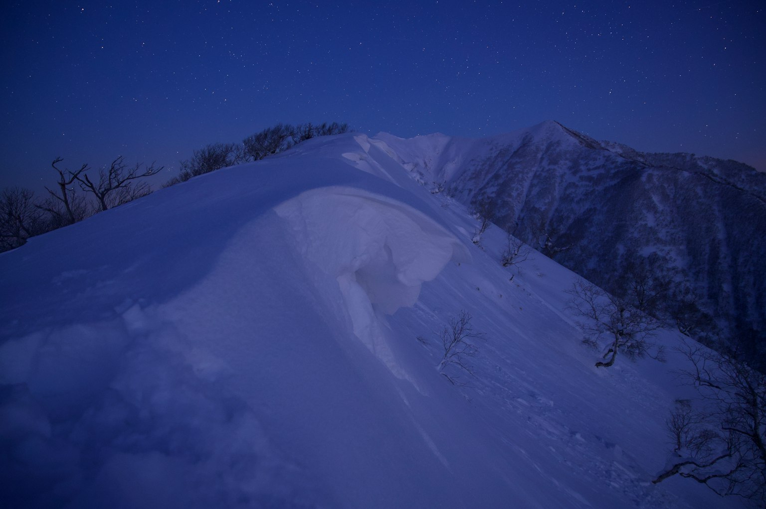Cresta montañosa cubierta de nieve iluminada por el crepúsculo