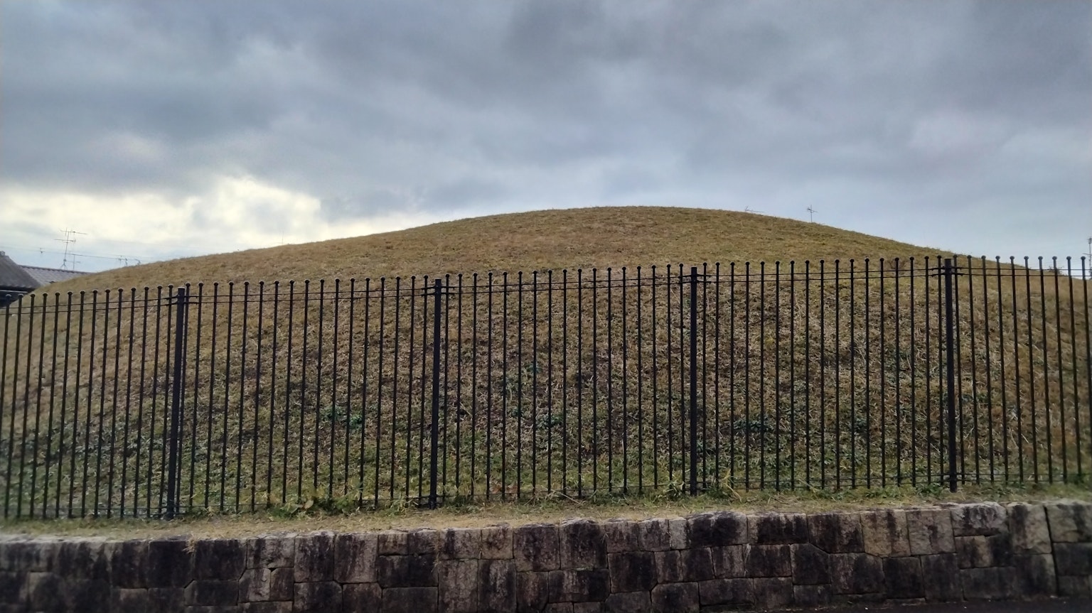 Paisaje con una colina verde y una cerca negra
