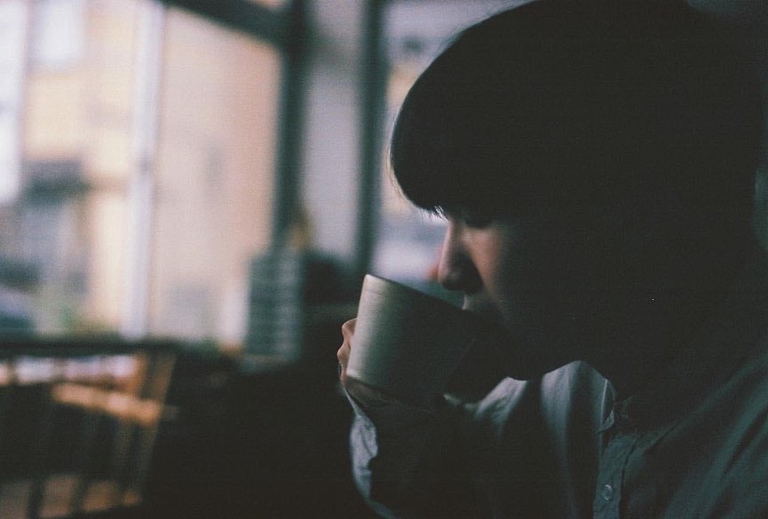 窓辺でコーヒーカップを手にする人物の横顔