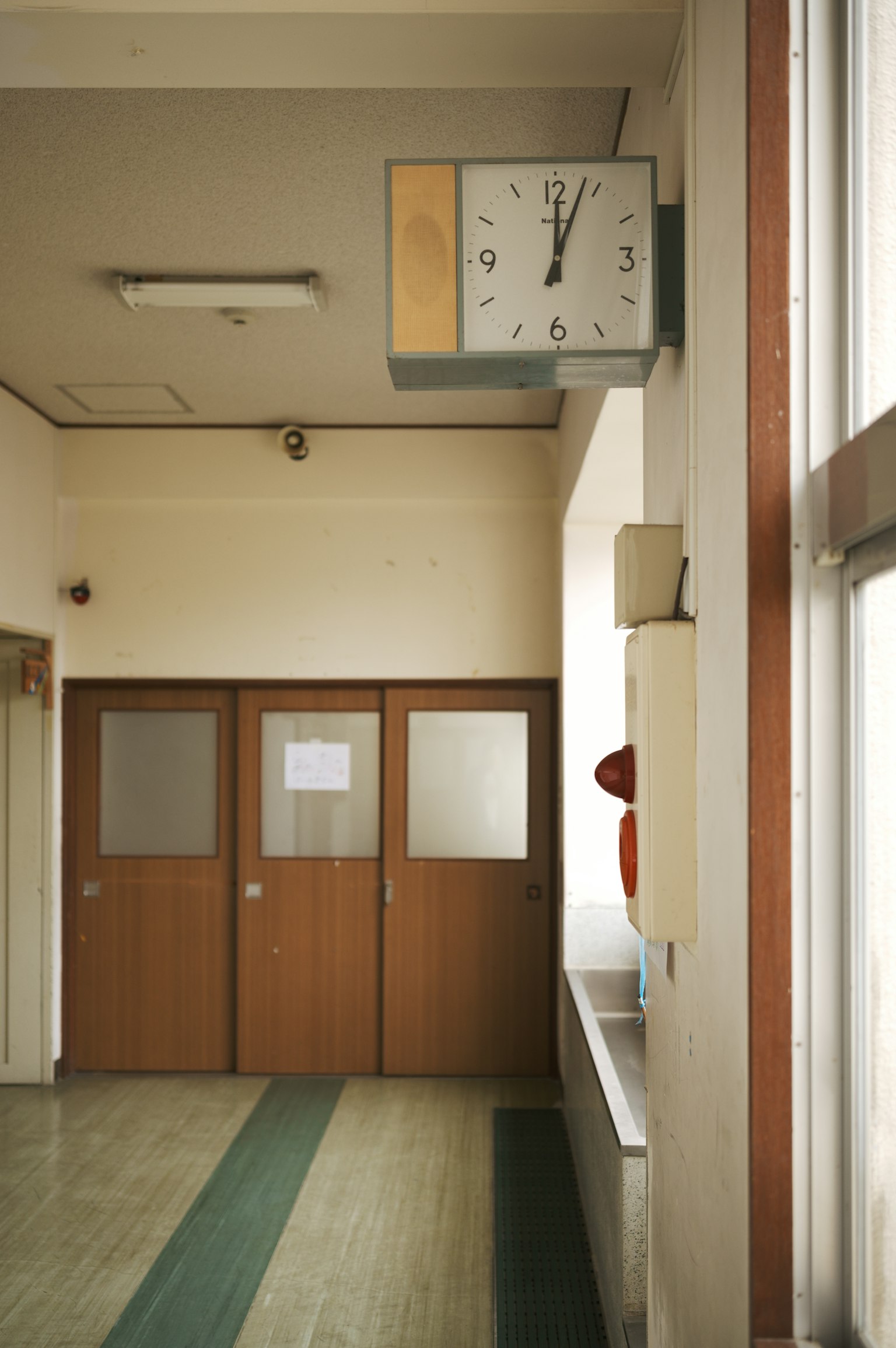 Interior de un viejo pasillo escolar con puertas de madera y un reloj
