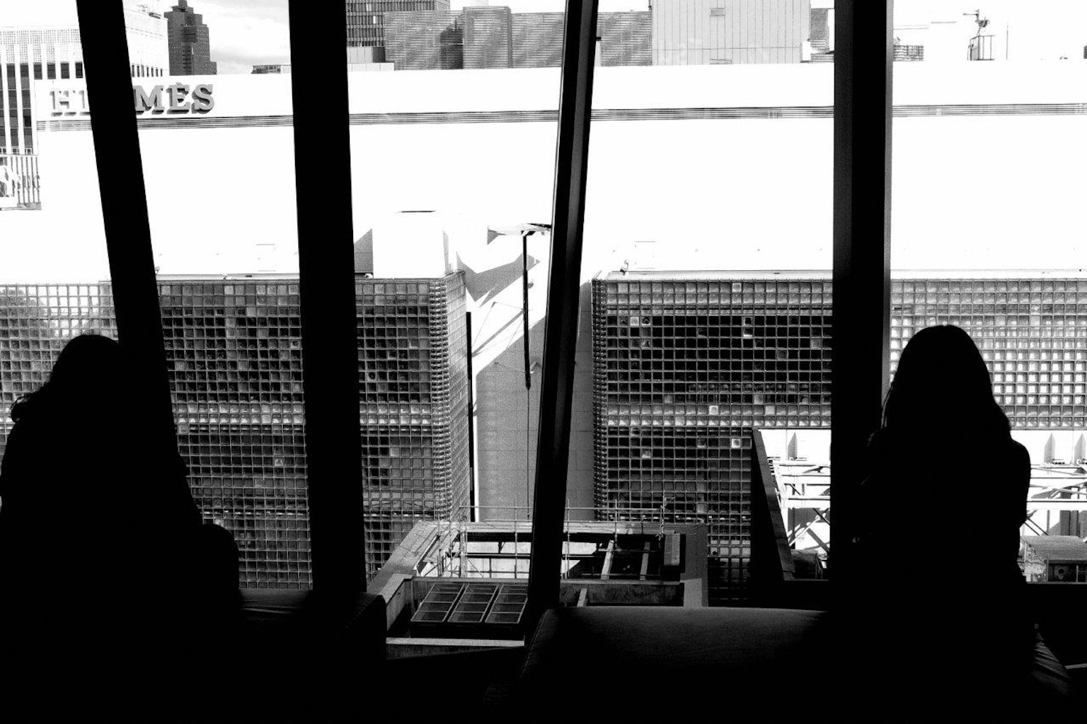 Silhouettes of two people sitting by a window with a cityscape in the background