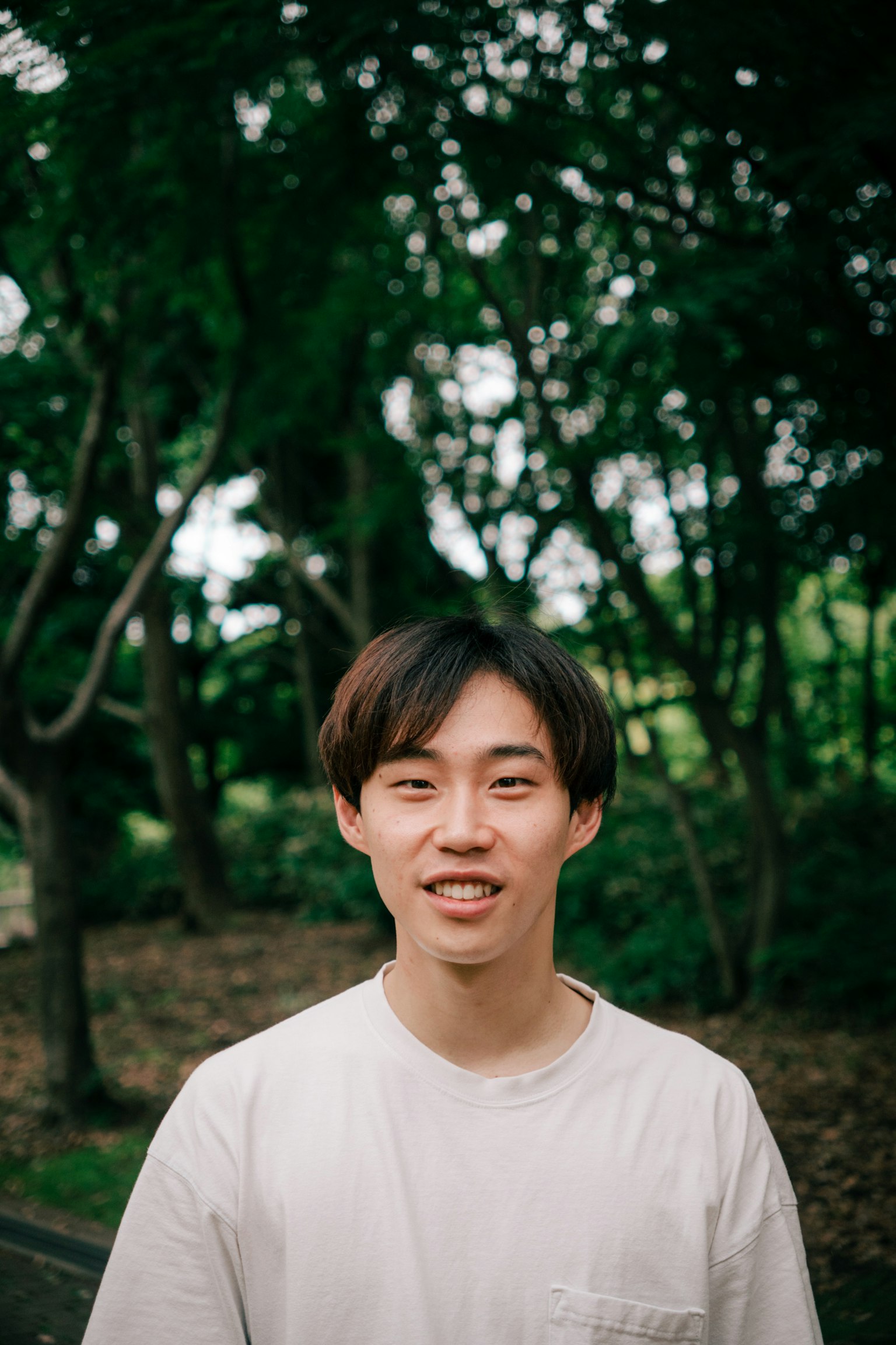 Portrait d'un jeune homme devant des arbres verts