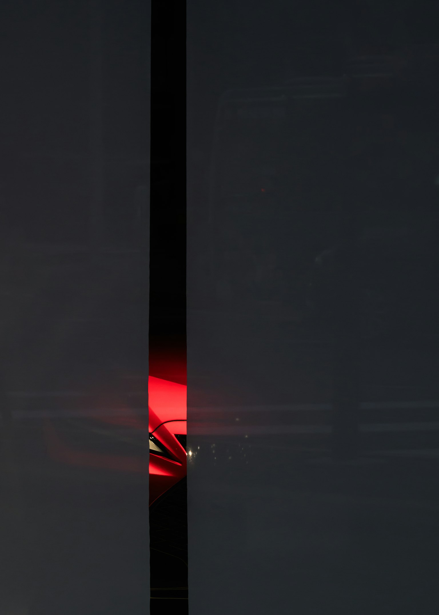 A simple composition with red light shining through a narrow gap in a black background
