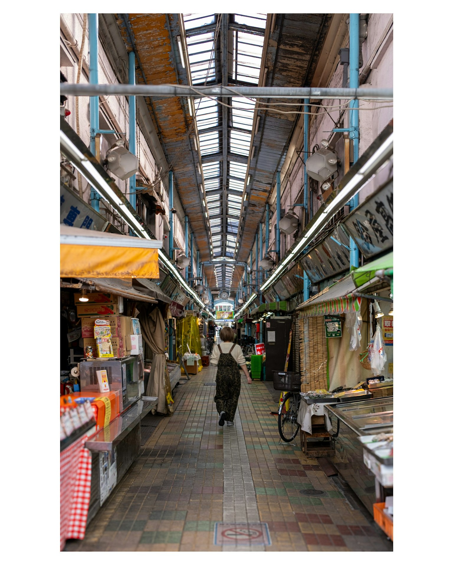 市場の通路に立つ人々と色とりどりの屋台