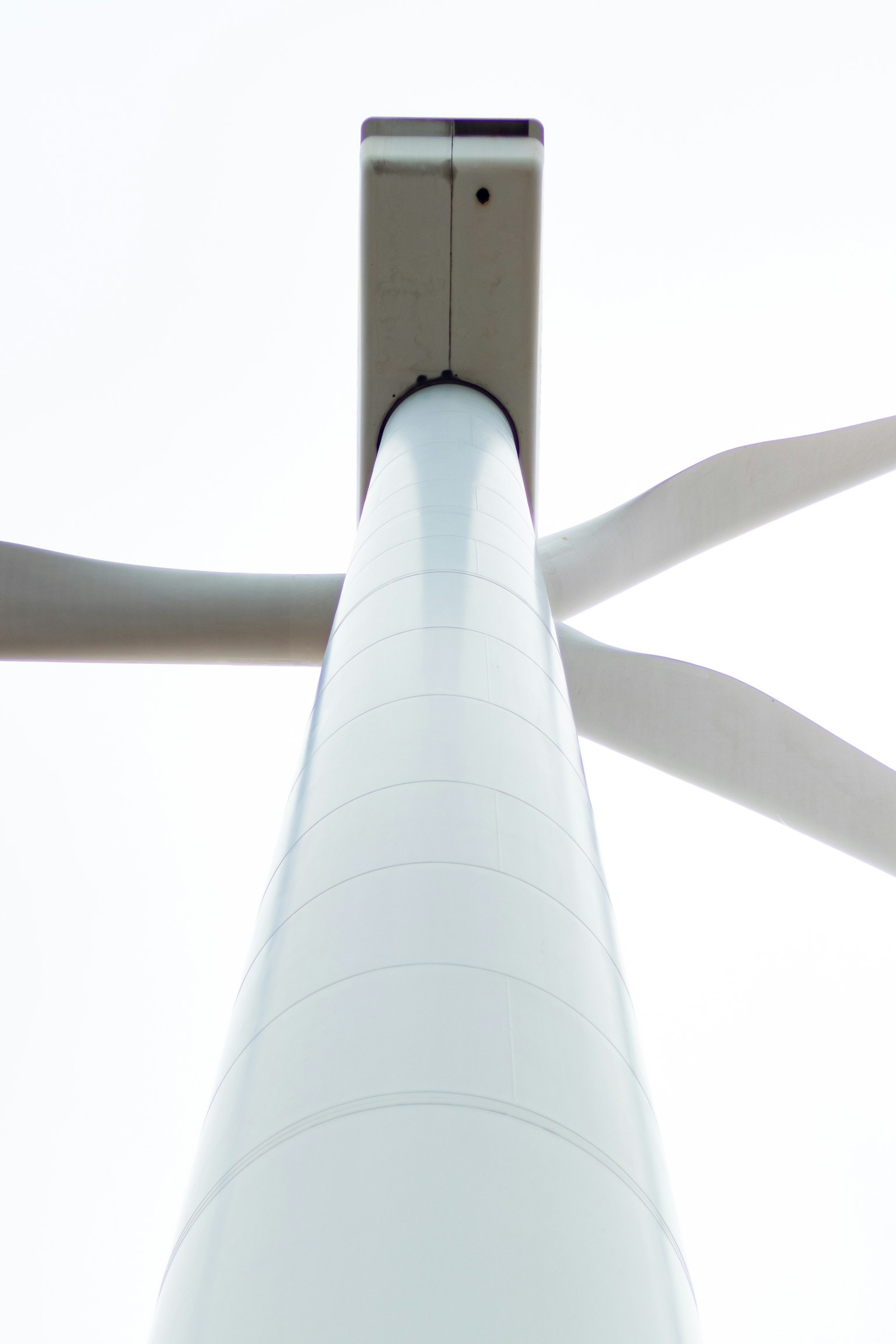 Foto vista desde abajo de una torre de turbina eólica Las aspas blancas se extienden hacia el cielo