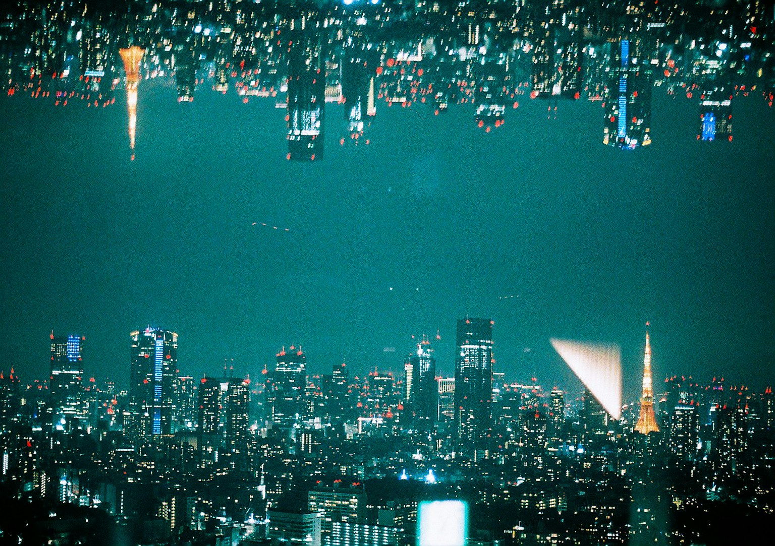 Immagine capovolta dello skyline notturno di Tokyo con vari grattacieli e riflessi di luci