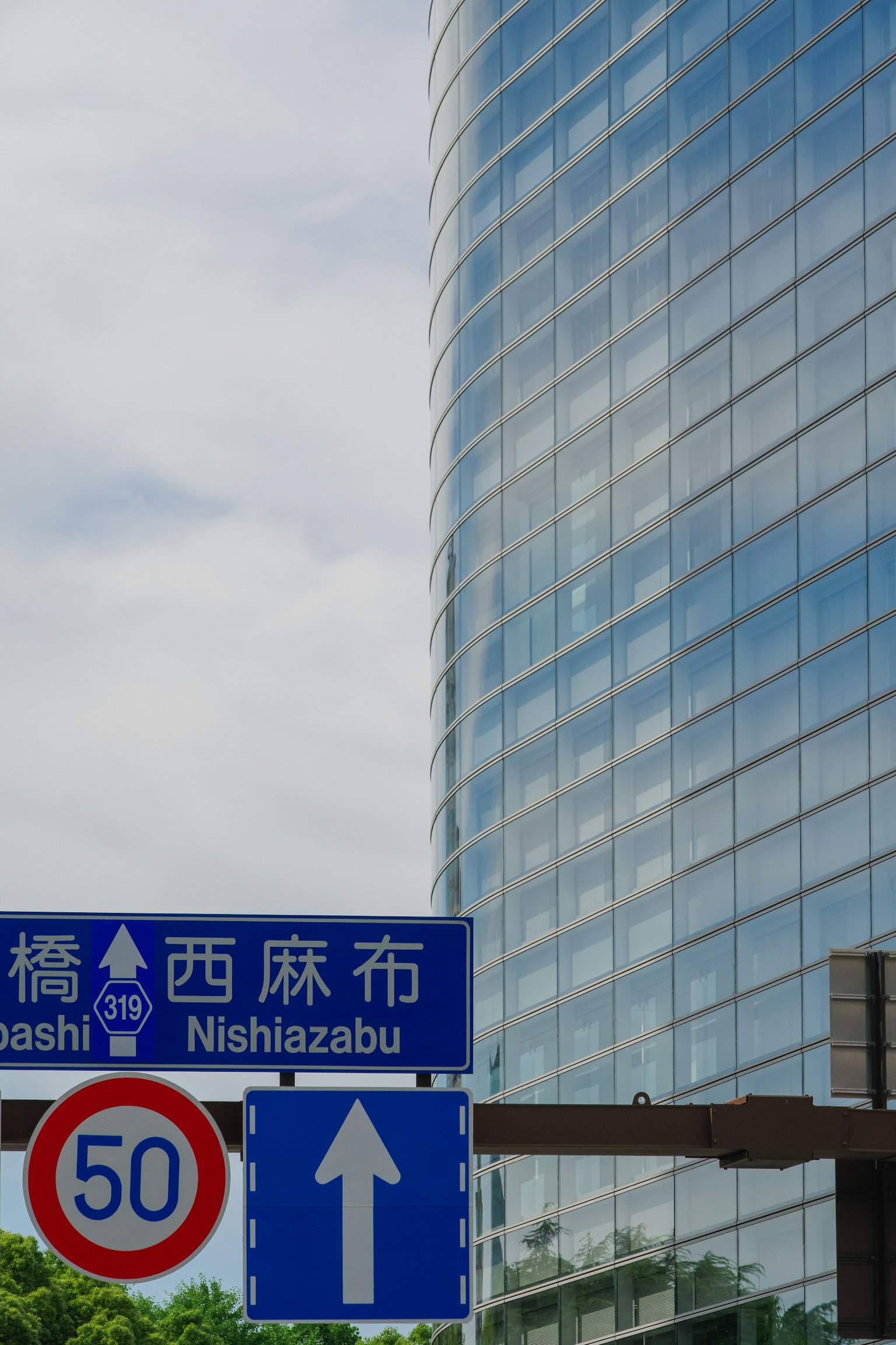 Segnale stradale per Nishiazabu con facciata di edificio moderno