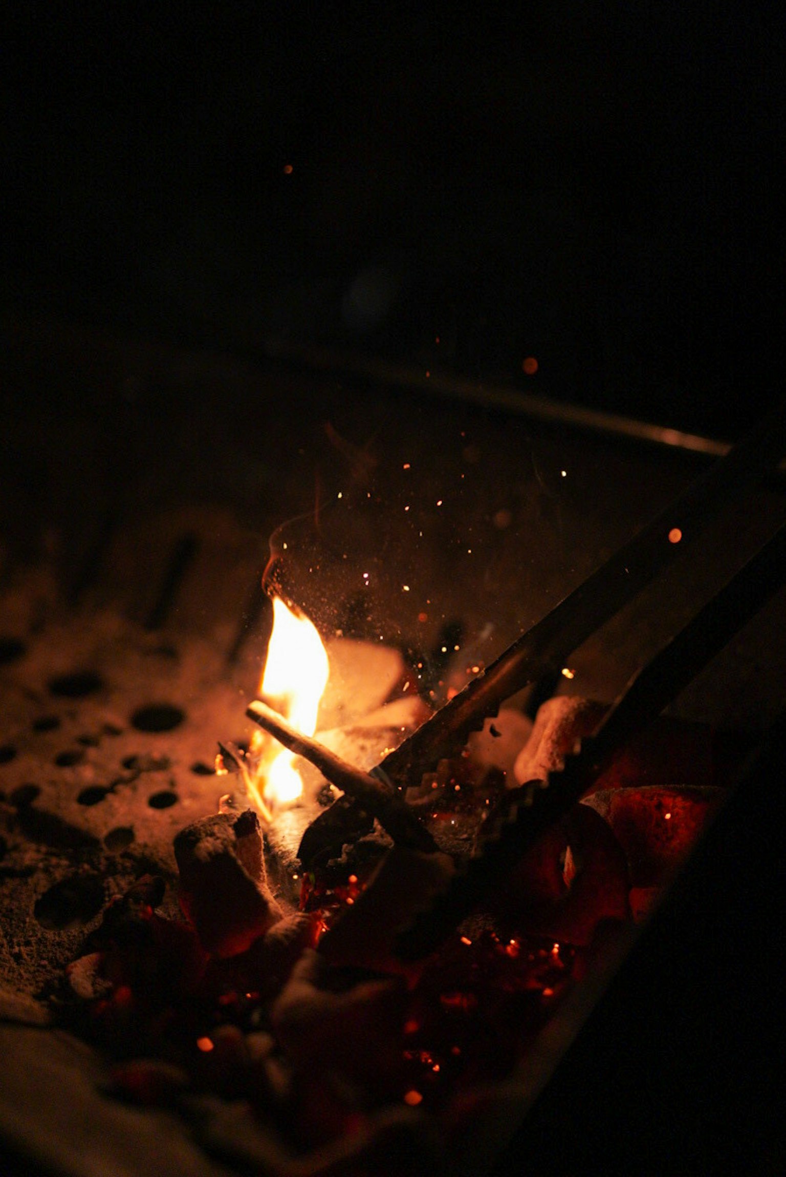 Nahaufnahme einer Flamme und Glut vor einem dunklen Hintergrund