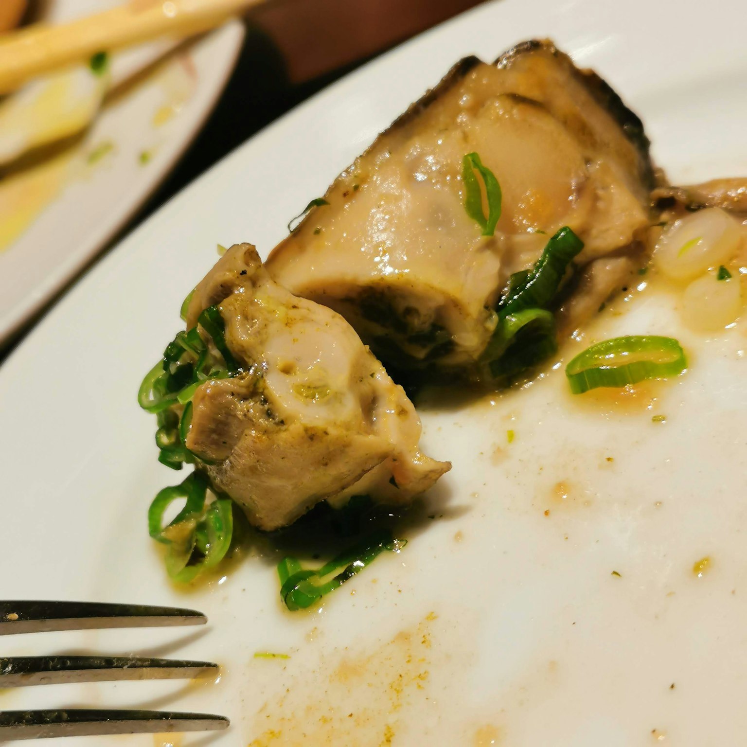 Primo piano di un piatto con un pezzo di pollo e cipollotti