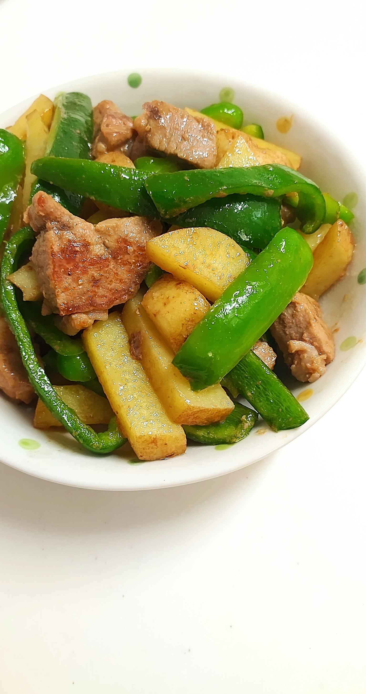 碗中盛有炒青椒和猪肉及土豆