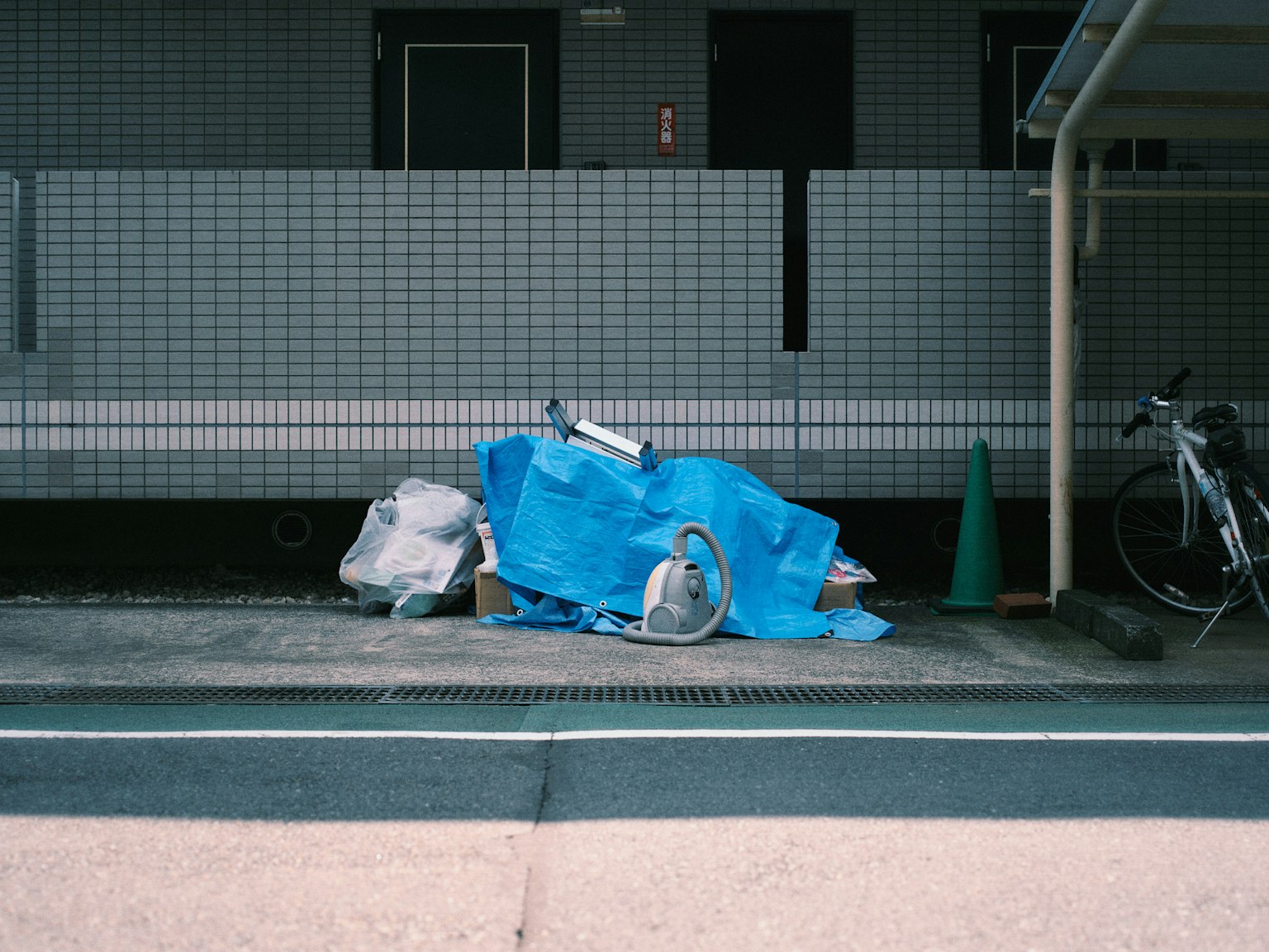 Un montón de basura cubierto con una lona azul junto a una bicicleta